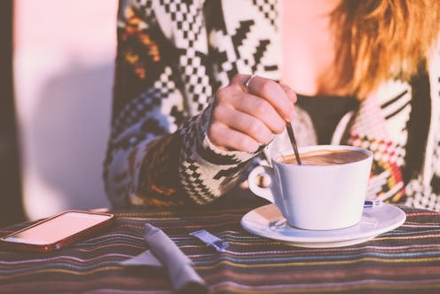A girl stirs her coffee with a spoon during staycation