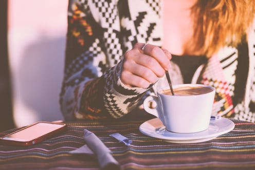 A girl stirs her coffee with a spoon during staycation