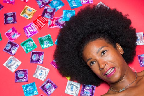 Curly and black-haired lady's face surrounded by many different condom packages
