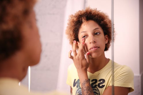 Girl with her index finger over her right eye while putting one makeup