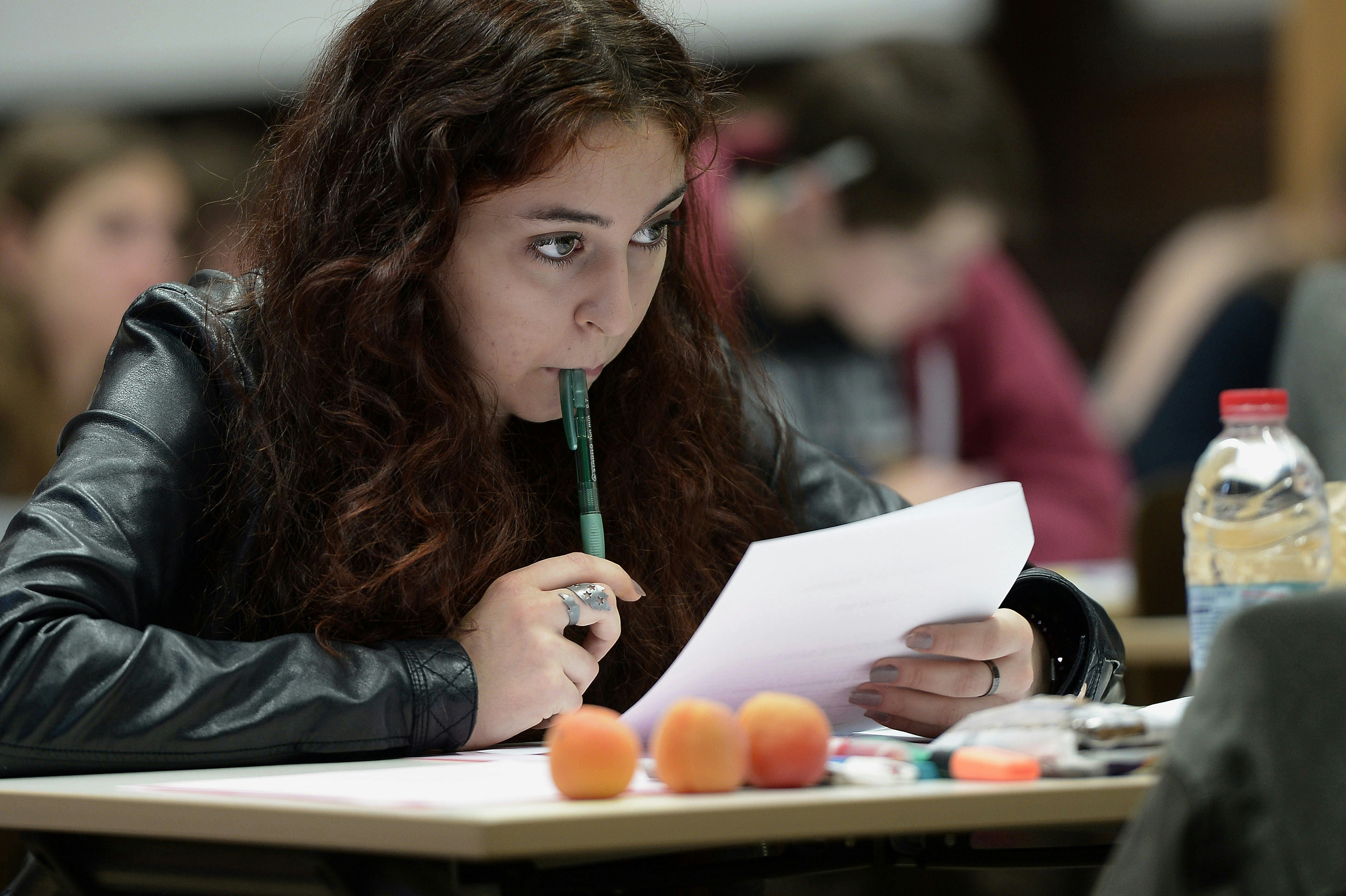 A girl with eating disorder holding a pen and paper while sitting in a classroom