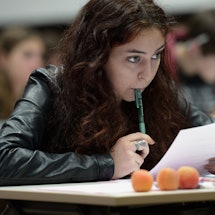 A girl with eating disorder holding a pen and paper while sitting in a classroom