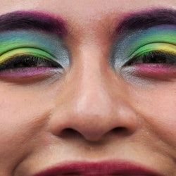 A person with rainbow flags painted on their eyelids. Queer meaning is very personal.