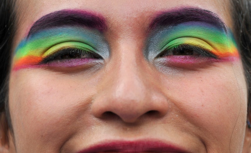 A person with rainbow flags painted on their eyelids. Queer meaning is very personal.