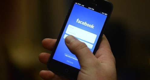 A person holding a phone with the Facebook login page open