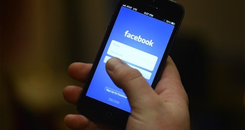 A person holding a phone with the Facebook login page open