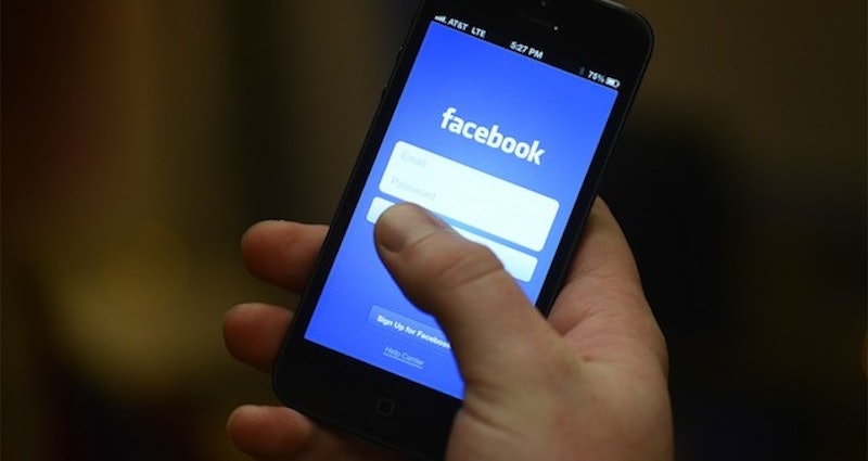A person holding a phone with the Facebook login page open