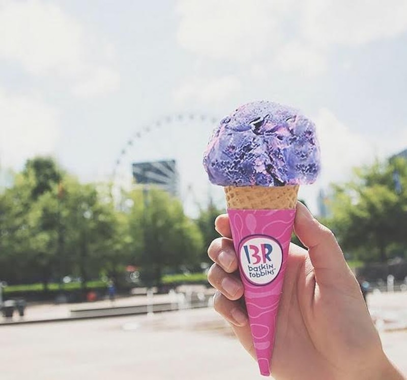 A scoop of Baskin-Robbins' ice cream in a cornet cone with a Ferris wheel in the background