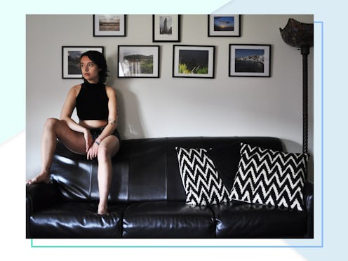 Meg Zulch in a black tank top and black underwear sitting on top of a leather couch