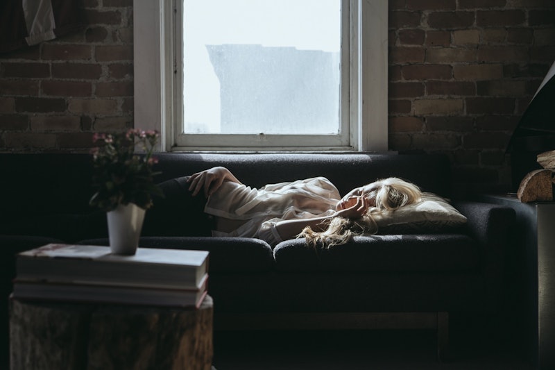 A woman that suffers from PCOS lying down alone on her sofa