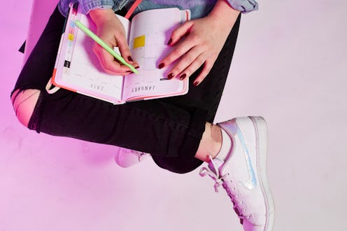 A girl writing in a journal that is placed over her crossed legs