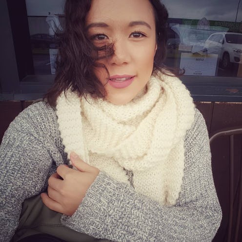 Gina M. Florio wearing a grey sweater and a white scarf, with her hair blowing in the wind.