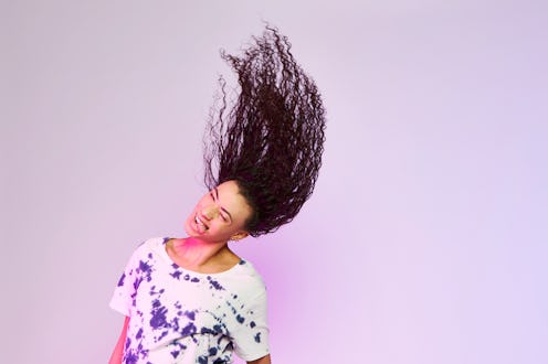 A woman in a white floral-patterned t-shirt flipping her long wet black hair