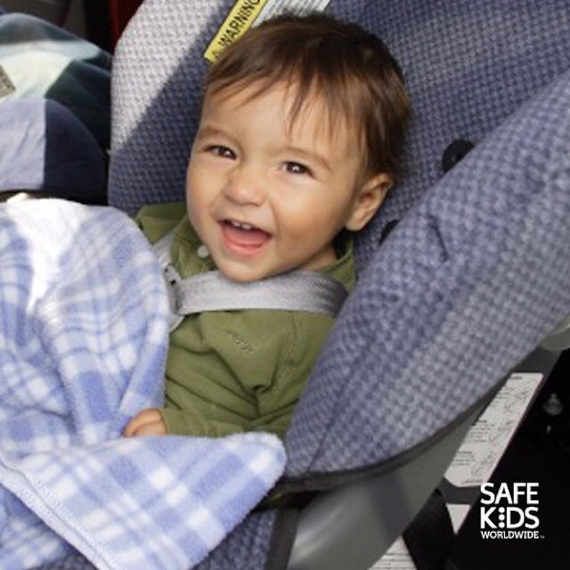 A toddler sitting in a car seat and smiling