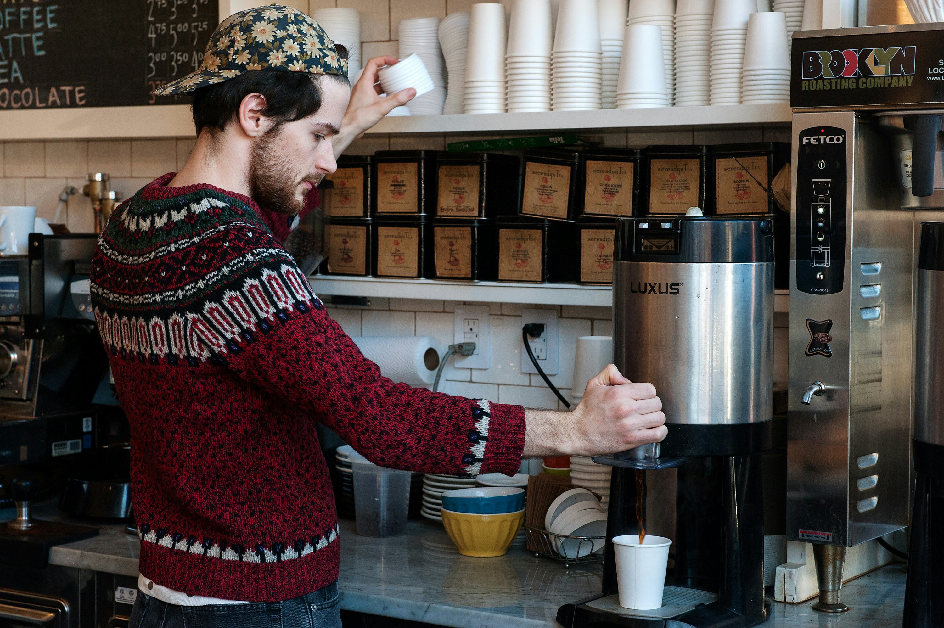 Young man makes his own coffee to go in a cafeteria