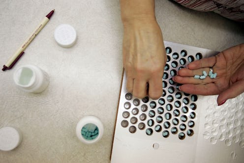 A woman taking pills out of the bottle and putting them inside a pill organizer