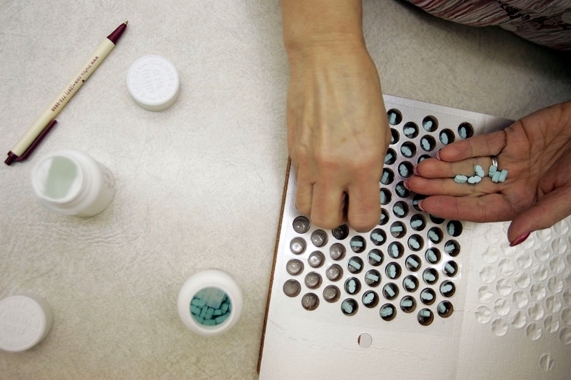 A woman taking pills out of the bottle and putting them inside a pill organizer