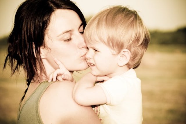 A young mother kissing her toddler son while holding him