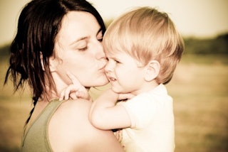 A young mother kissing her toddler son while holding him