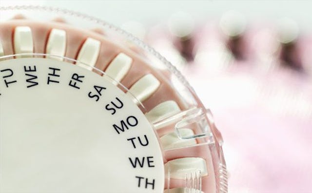A close-up of a white-pink round box with contraception pills