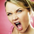 Angry pregnant blonde woman wearing a pink shirt with a face that looks like she is yelling