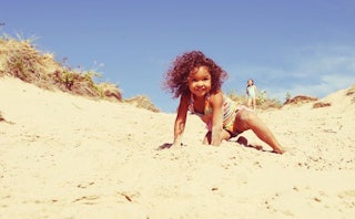 A child playing on a sandy beach on a bright summer day