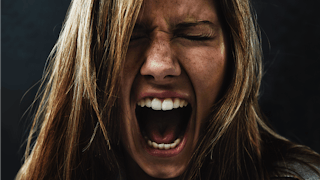 A portrait of a woman screaming and experiencing rage because of PPD 