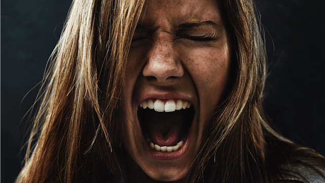 A portrait of a woman screaming and experiencing rage because of PPD