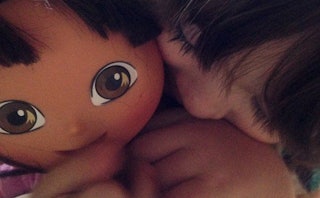A girl hugging her Dora the Explorer doll