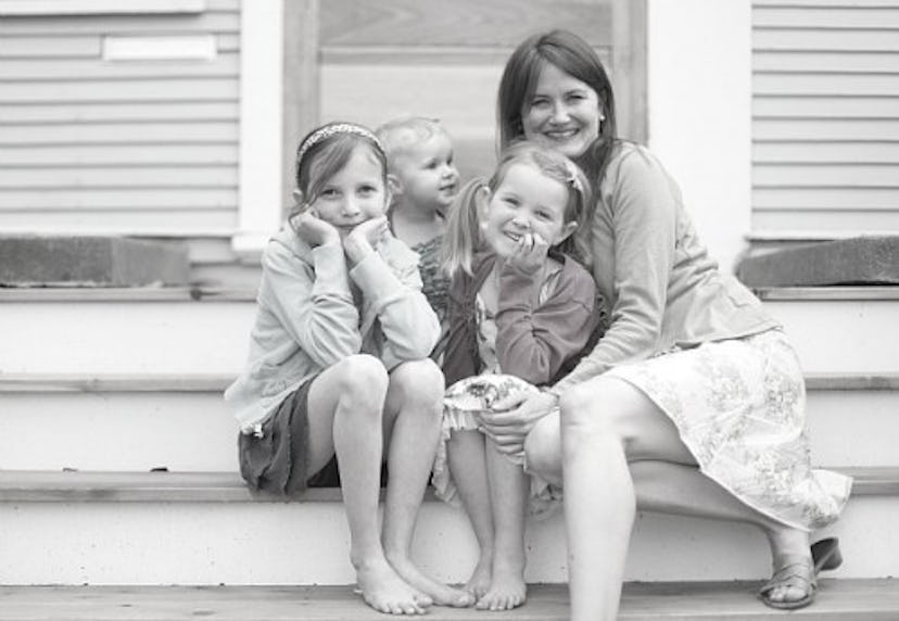 An older mother and her three daughters posing and smiling while sitting on a porch. 