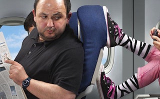 A man trying to read papers on a plane while a kid's feet pushing his seat trying to survive his fli...