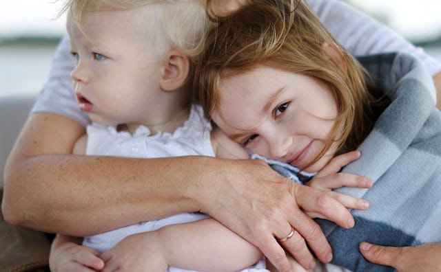 A parent hugging their little baby and daughter.