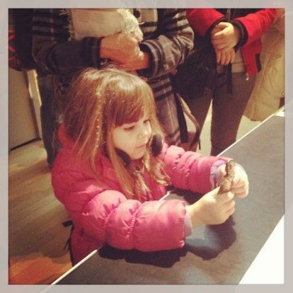 A girl with a pink jacket playing with a small figure in the National Army Museum  