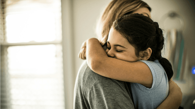 A young daughter giving her mother a big hug