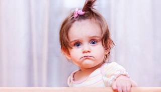 A toddler girl with blue eyes with a confused facial expression