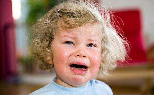 Blonde curly hair girl wearing a blue shirt while she's crying