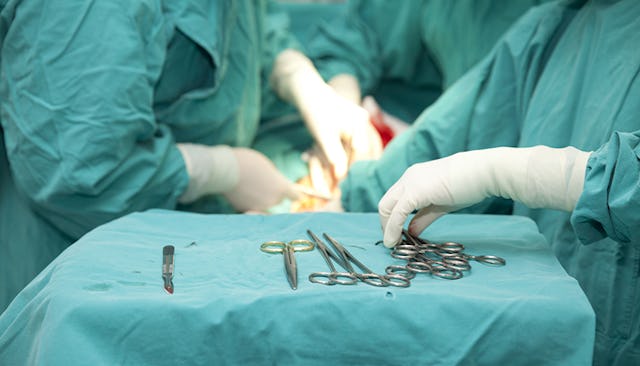 A surgeon performing a C-section on a patient surrounded by assistants