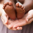 A mother's hands holding little feet of a newborn.