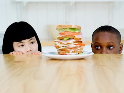 Two kids looking at a huge sandwich in front of them.
