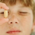 A young boy holding a pill that is used after allergy food reaction