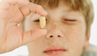 A boy with food allergies holding a peanut and looking at it with one eye closed