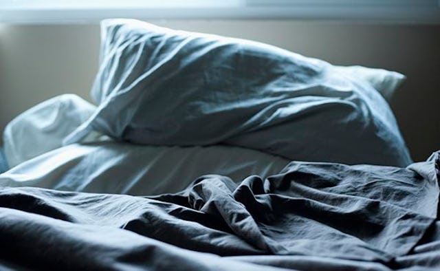An Unmade Bed With Gray Sheets