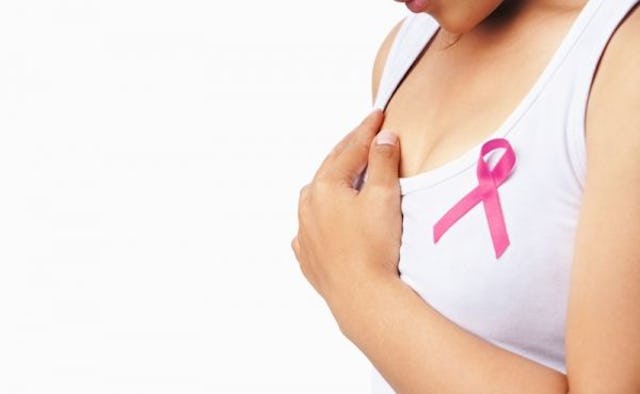 A woman wearing a breast cancer awareness ribbon on a white top while performing a self-examination ...