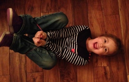 A kid smiling on the floor, hogtied with a Rainbow Loom rubber band repurposed as Behavior Bands.