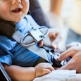 A small boy sitting in a baby car seat with tied belt