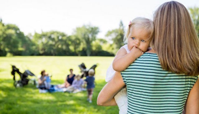 A mother holding her baby during a picnic with other moms and kids