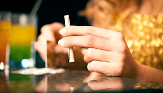 A woman holding money rolled into a tube-like shape on a table