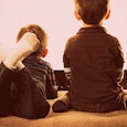 Two boys sitting and laying down in front of the big TV 