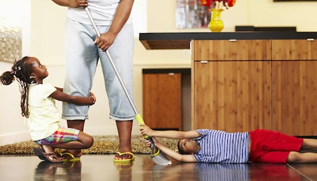Children hanging on their stay-at-home mom while she is cleaning