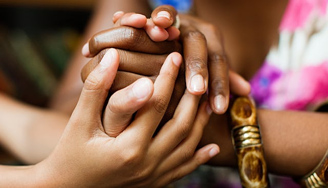 A close-up of a child's and an adult's hand together with their intertwined fingers